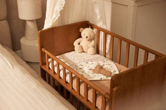 Gigoteuse Naissance Cocoon 0-3 mois Riverside - Jollein dans un berceau en bois avec un ours en peluche.