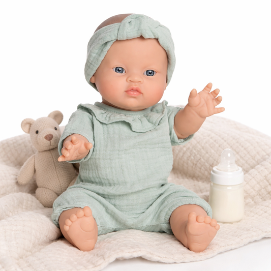 Poupée bébé Paula Bobble verte assise sur fond blanc avec tenue en gaze de coton et bandeau assorti